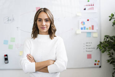 Confident businesswoman standing against whiteboard at office - GIOF09372