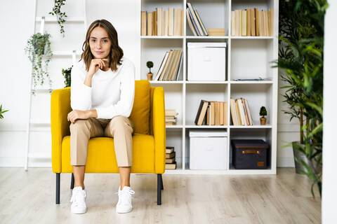 Young businesswoman sitting with head in hands on sofa at office stock photo