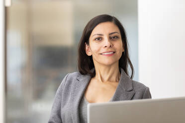 Businesswoman using laptop while working at home - SGF02712