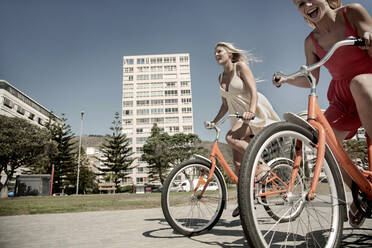 Junge Freundinnen radeln im Sommer auf der Promenade - AJOF00459