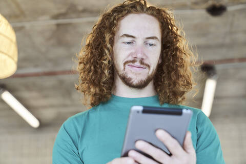 Handsome man surfing through internet on digital tablet at home stock photo