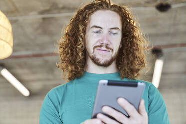 Gut aussehender Mann surft zu Hause auf einem digitalen Tablet im Internet - FMKF06642