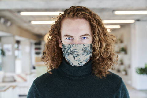 Mid adult man wearing protective face mask at studio apartment stock photo