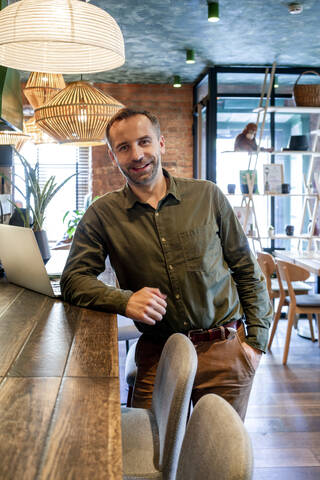 Businessman with hands in pockets standing at cafe stock photo