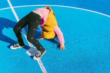 Girl doing acrobatic activity on soccer court during sunny day - ERRF04670