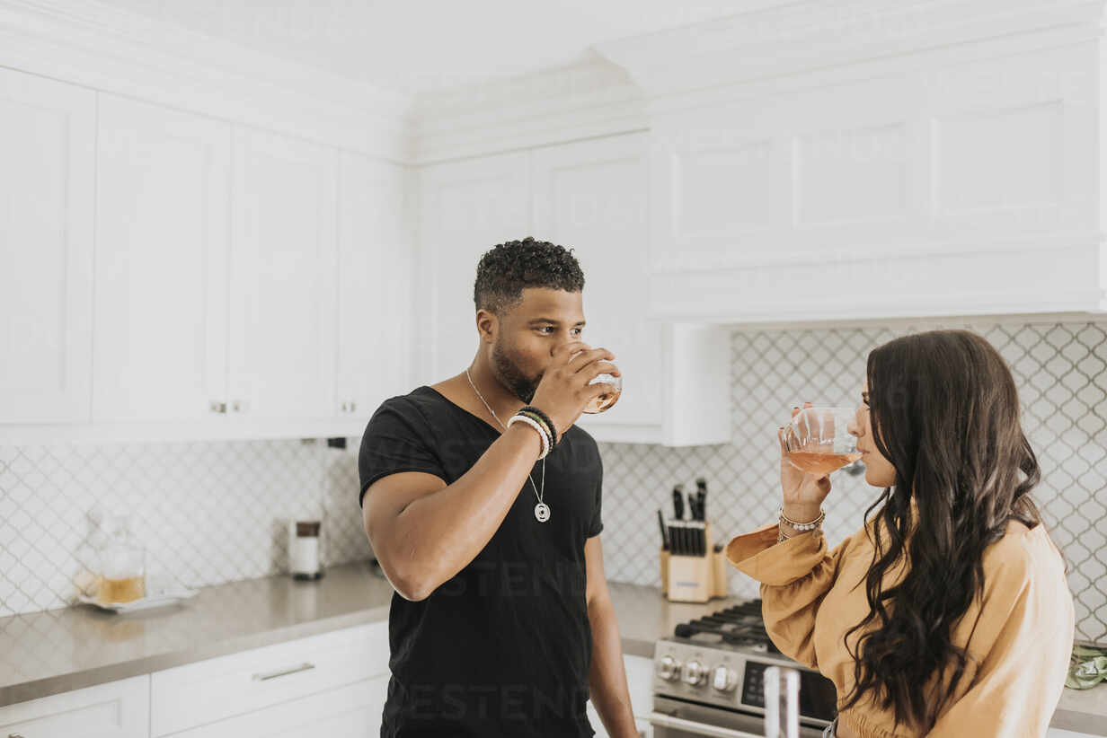 https://us.images.westend61.de/0001473375pw/couple-drinking-wine-while-standing-in-kitchen-at-home-SMSF00368.jpg