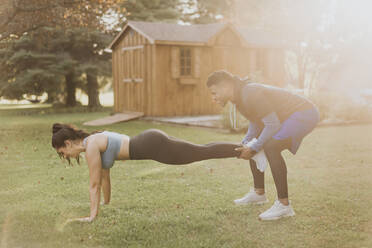 Man holding woman legs while exercising at backyard - SMSF00419