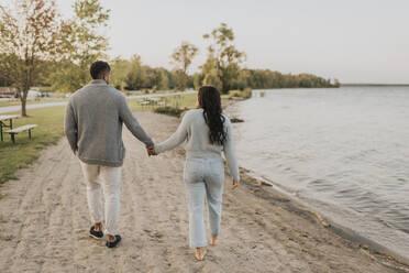 Paar hält Hände beim Spaziergang am See - SMSF00454