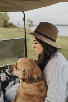 Frau lächelt, während sie mit Hund im Golfwagen sitzt - SMSF00467