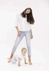 Mutter stehend und Tochter krabbelnd vor weißem Hintergrund im Studio - DHEF00499