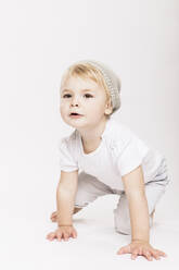 Cute little toddler girl crawling in studio against white background - DHEF00503