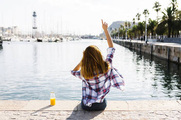 Junge Frau mit erhobenen Armen und Blick auf das Meer an einem sonnigen Tag - XLGF00676