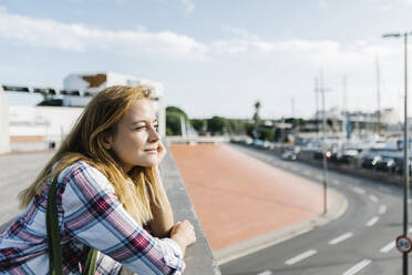 Thoughtful woman with hand on chin standing in city during sunny day - XLGF00687