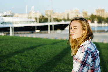 Blond woman looking away while standing in public park on sunny day - XLGF00719