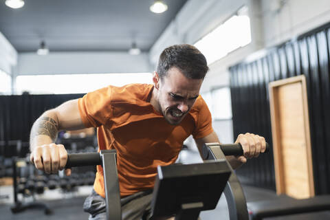 Sportler beim Training an einem Sportgerät im Fitnessstudio, lizenzfreies Stockfoto