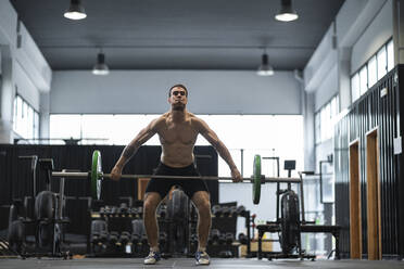 Männlicher Sportler hebt eine Langhantel im Fitnessstudio - SNF00723