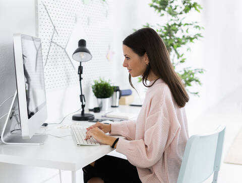 Young female influencer using computer at home stock photo