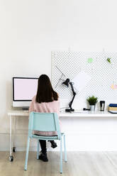 Female blogger using computer at desk in loft apartment - GIOF09491