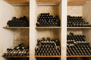 Stapel alter Weinflaschen in einem Regal im Keller - EGAF00967
