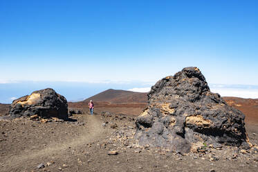 Senior man hiking along trail stretching across brown barren landscape of Tenerife island - WWF05557