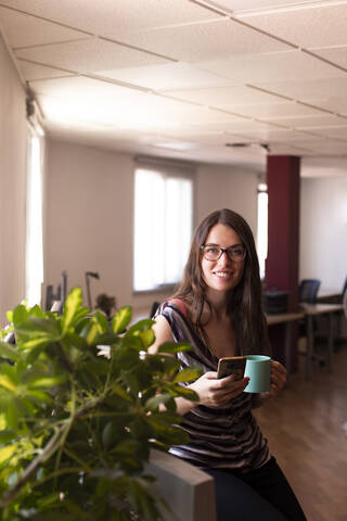 Smiling young female entrepreneur having coffee during office break stock photo