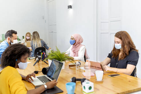 Business people wearing face mask while working at office - MPPF01180