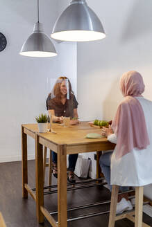 Coworker eating food while sitting at screen partition table at office - MPPF01214