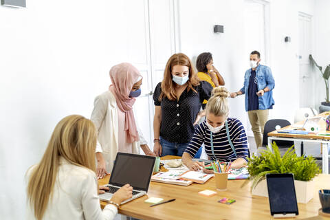 Women working while standing with coworker in background at office stock photo