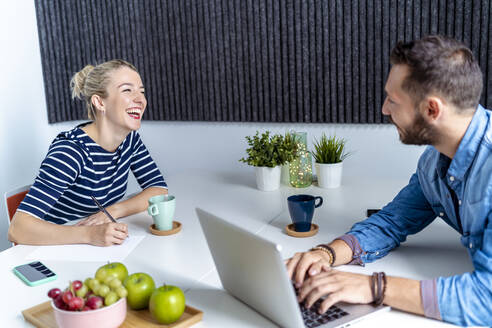 Smiling coworker working while sitting at office - MPPF01233