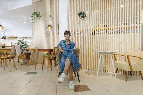 Geschäftsfrau sitzt auf einem Stuhl in einem Cafe - GUSF04561