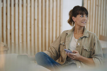 Weibliche Unternehmerin, die in einem Café sitzt und ihr Smartphone benutzt - GUSF04617