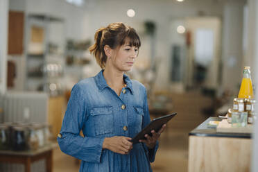 Unternehmerin, die ein digitales Tablet benutzt, während sie in einem Café steht - GUSF04618