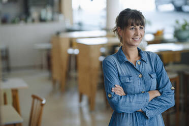 Female entrepreneur with arms crossed standing in coffee shop - GUSF04628