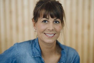 Close-up of female owner standing against wall in cafe - GUSF04629