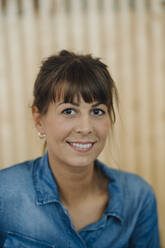 Smiling female owner standing against wall in cafe - GUSF04630