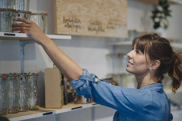 Businesswoman arranging glass jar on shelf in cafe - GUSF04664