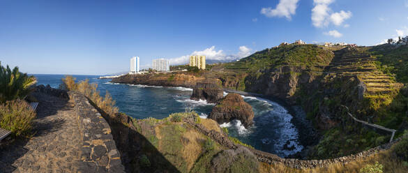 Spanien, Provinz Santa Cruz de Tenerife, Puerto de la Cruz, Küstenklippen mit Stadt im Hintergrund - WWF05593