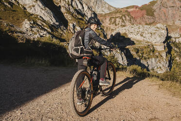 Smiling woman on electric mountain bike standing at Somiedo Natural park, Spain - DMGF00245