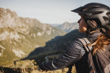 Mountain biker with bicycle standing while admiring mountain view at Somiedo Natural Park, in the north of Spain - DMGF00246