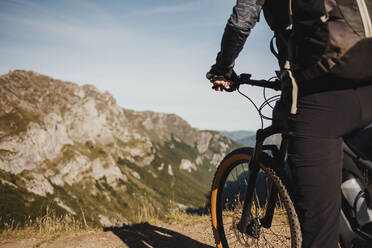 Female mountain biker on electric bicycle standing against mountain at Somiedo Natural Park, Spain - DMGF00247