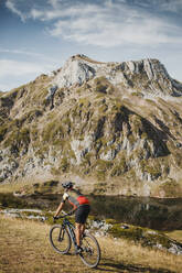 Mountainbiker beim Fahrradfahren auf einem Berg am See im Naturpark Somiedo, Spanien - DMGF00251