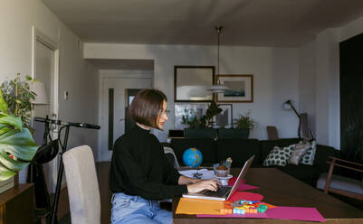 Geschäftsfrau, die konzentriert am Laptop arbeitet, während sie zu Hause sitzt - VABF03808