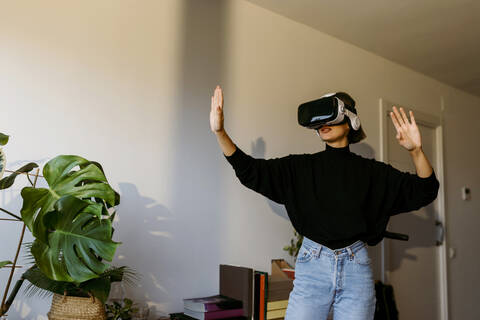 Woman wearing virtual reality simulator while standing at home stock photo