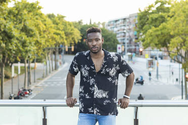 Young man leaning on railing at bridge over street in city - PNAF00050