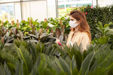 Redhead businesswoman holding digital tablet while examining plant at garden center stock photo