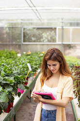 Geschäftsfrau, die ein digitales Tablet benutzt, während sie in einem Gartencenter steht - LJF01862