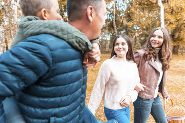 Glückliche Mutter und Tochter gehen spazieren, während der Vater seinen Sohn im Park von Cannock Chase huckepack trägt - WPEF03509