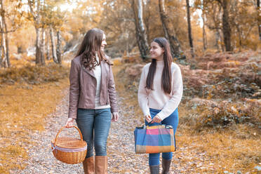 Mother and daughter looking at each other while walking in Cannock Chase park during autumn - WPEF03511