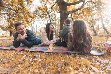 Glückliche Familie, die im Herbst im Park liegt und genießt - WPEF03538