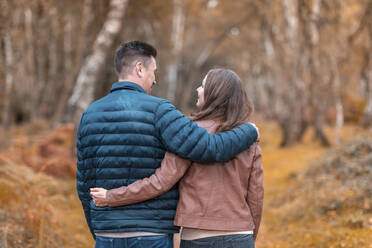 Heterosexual couple with arms around standing in Cannock Chase park during autumn - WPEF03550